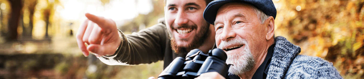 Mature man with son outside looking with binoculars.